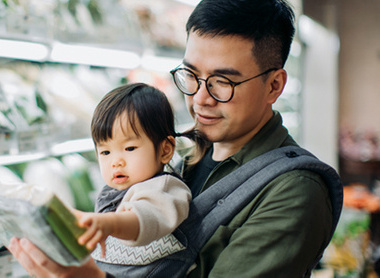 Man and baby at supermarket looking at healthy food