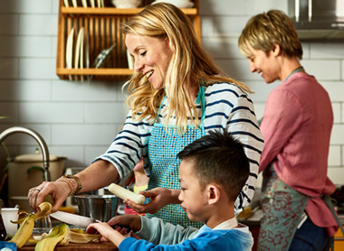 Two women in kitchen with small child, cooking