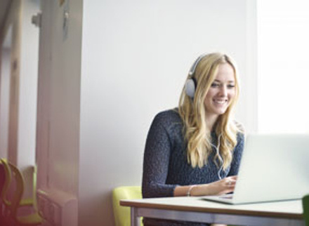 Woman with headphones on whilst using laptop