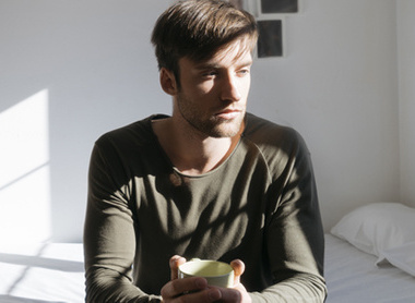 Man sitting on bed looking sad