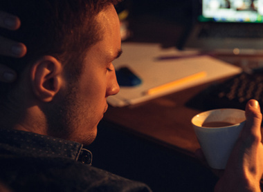 Man in dark on laptop looking stressed