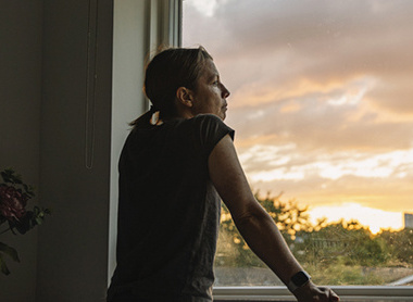 Woman looking out of window looking bereft