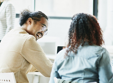 Two people at work talking and laughing