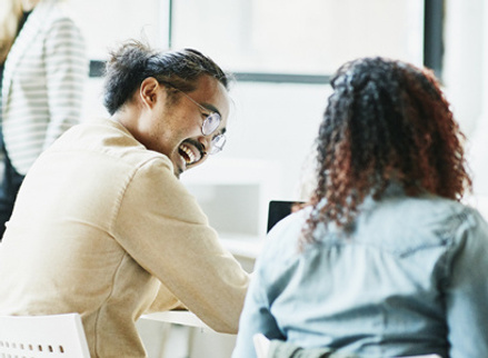 Two people at work talking and laughing