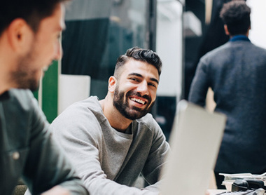 Two men at work talking and smiling