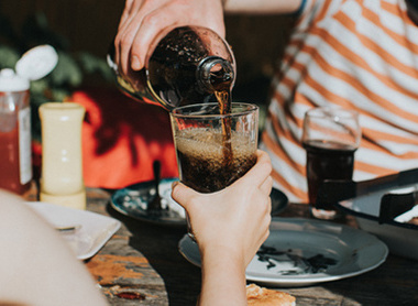 Someone pouring a fizzy cola drink in a glass 