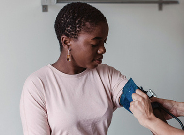 Woman getting their blood pressure taken by someone in scrubs