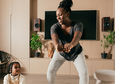 Mother working out doing gentle exercises with child in front room 