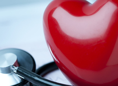 A red plastic heart next to a stethoscope