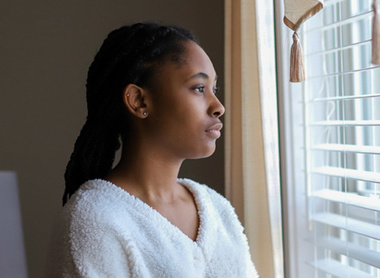 Woman looking out of window looking sad